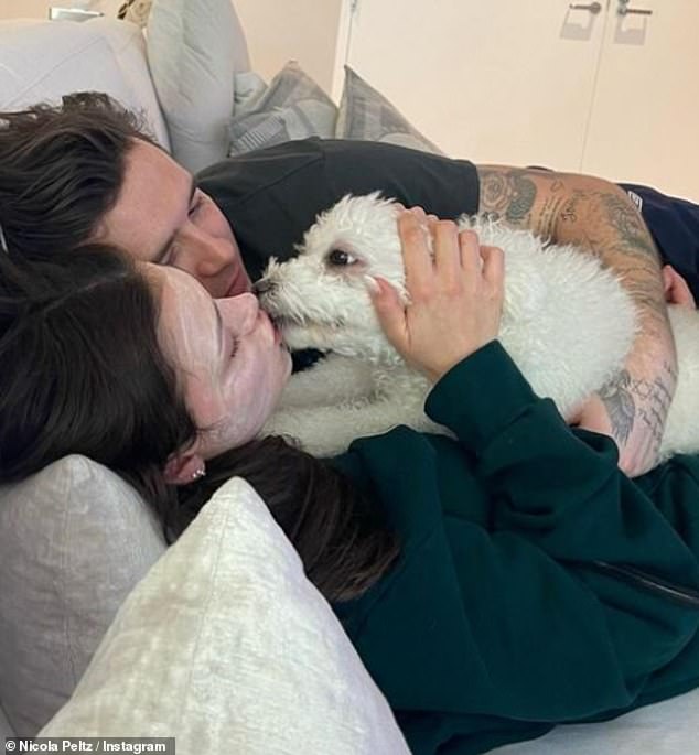 Cute: Nicola Peltz, 28, and Brooklyn Beckham, 23, shared a kiss with their pet as they snuggled up for a relaxing pampering session on Sunday