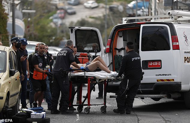 A man on a stretcher, suspected of being the attacker, is carried into a police van by Israeli police officers at the scene of a shooting near the Old City of Jerusalem.