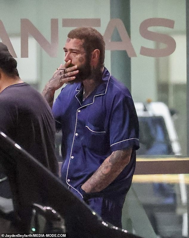 Post Malone smoked a cigarette in expensive silk pajamas when he landed in Sydney on Monday.  The 27-year-old American rapper is on tour in Australia with the Red Hot Chili Peppers