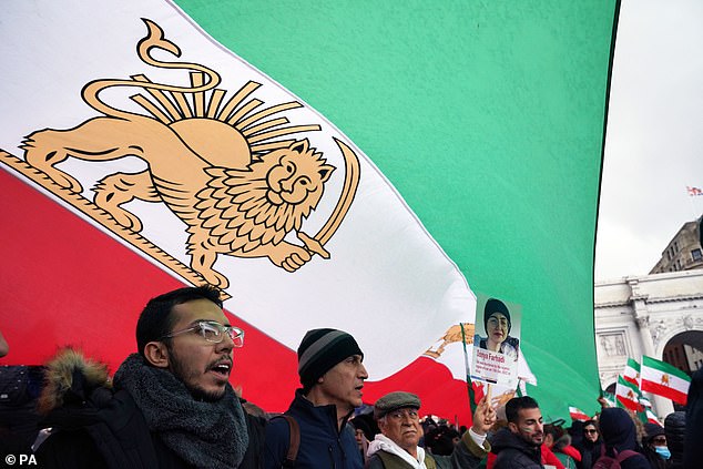 Protesters take shelter from the rain under pre-revolutionary Iranian flags, changed in 1980