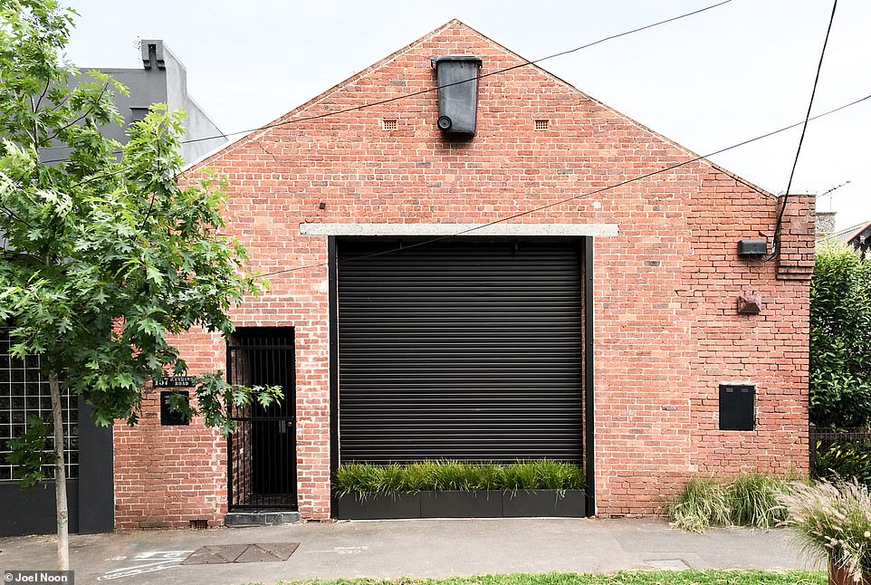 A wheelie bin hangs from the brick exterior of an unassuming former warehouse in Melbourne as a hint of the building's past.  The converted factory now houses an amazing contemporary house.