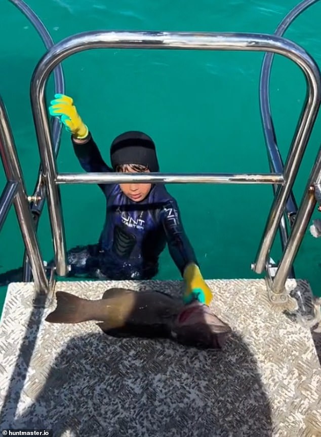 Young spearfisherman Manni hauls his fish up to the diving platform behind the boat.