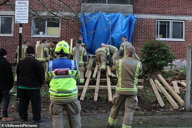 Fire crews are seen building a ramp to get the 50-stone man out of his ground-floor council house in Acton, west London, in an operation estimated to cost around £10,000.