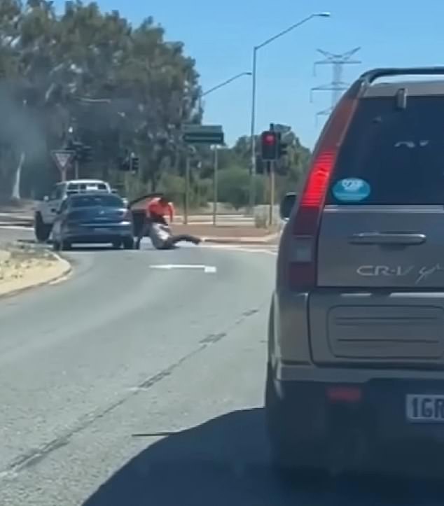 Caught on dash cam footage, a man (pictured) wearing a high-visibility orange shirt, shorts and work boots is seen brutally throwing the taxi driver to the ground next to his vehicle