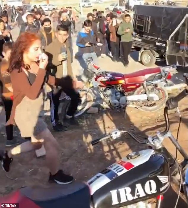 Shocking footage shows a girl wearing a headscarf as she runs away from a large crowd of boys and men who attacked her for dressing 'immodestly' at a motorcycle event in Iraq.