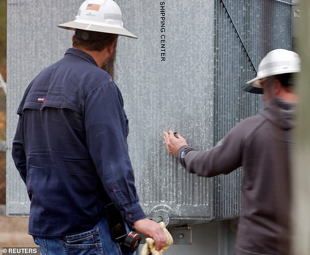 Duke Energy workers inspect what they said was one of three bullet holes that paralyzed an electrical substation after the Moore County sheriff said the vandalism caused a power outage.