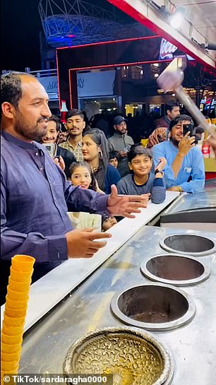 The customer takes the ice cream from the Turkish seller