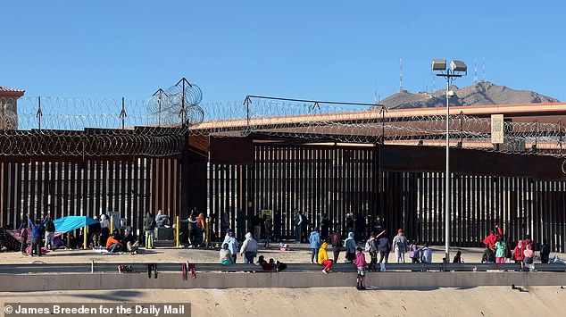 Migrants gather at the border fence around El Paso after crossing the Rio Grande into the United States.  Here they wait for border agents to open a gate and start processing them