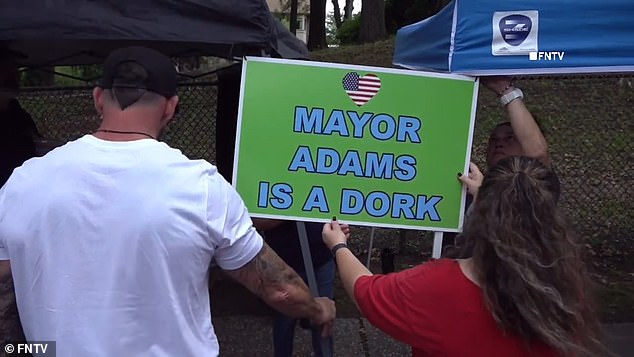 “Mayor Adams is a dork,” one sign read.  Adams has said repeatedly that the city is overwhelmed by the roughly 100,000 migrants who have poured into the city in the past year.