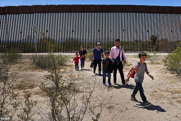 A family of five claiming to be from Guatemala and a man claiming to be from Peru, wearing a pink shirt, walk through the desert after breaking down the border wall in the Tucson sector of the US-US border on August 29, 2023. crossed into Mexico.