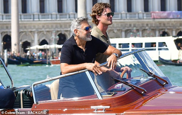 Fun: George looked typically handsome in a navy blue short-sleeved shirt and seemed to be having a good time as the boat moved through the water