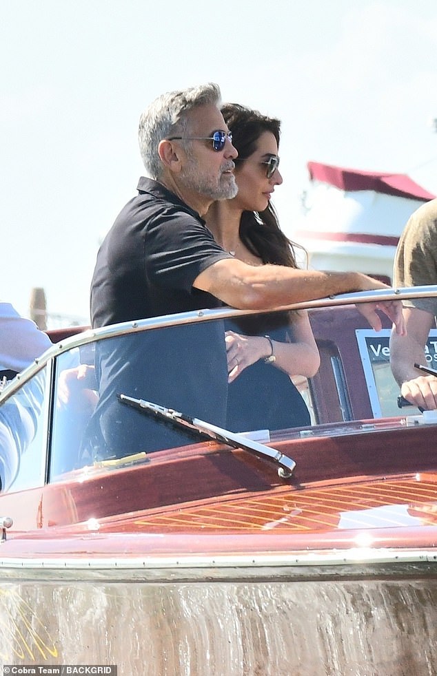 Smitten: George reached out to support Amal and made sure she boarded safely before the couple was pictured with their arms around each other