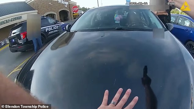 Footage shows one officer communicating with the victim at her window, while another stands in front of the hood of her car