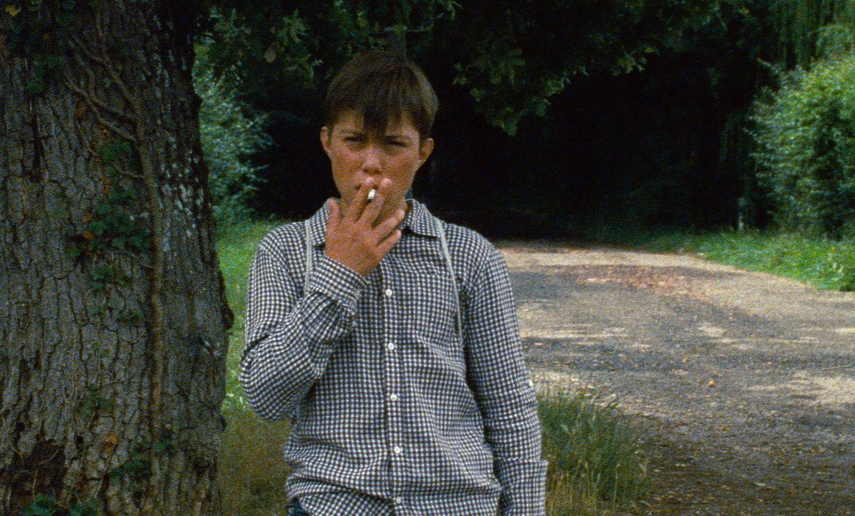 A very young boy smokes a cigarette in a grainy image from Astrakhan