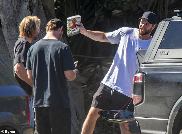 Owen Wright's autobiography, Against The Water, was published in August and he (with long blonde hair) donates an autographed copy to actor Chris Hemsworth before going surfing