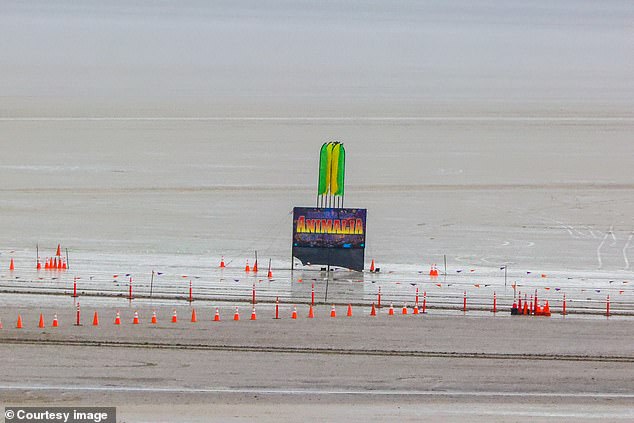 Traffic cones are reflected in the water that overlays the sand expanses of the desert