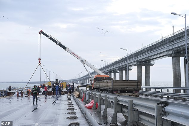 Workers repair the side of damaged spans of the road section of the Crimean Bridge connecting the Russian mainland and the Crimean peninsula across the Kerch Strait during restoration works, November 19, 2022