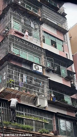 A man can be seen climbing up the side of the building to help