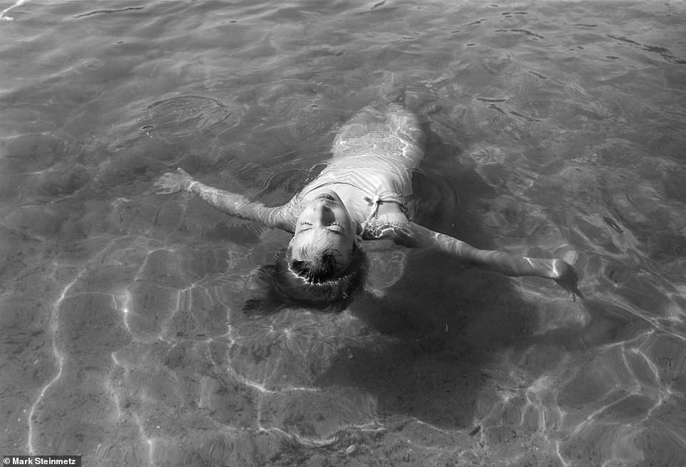 A young girl takes a dip in the water as the sun shines during a long day with friends