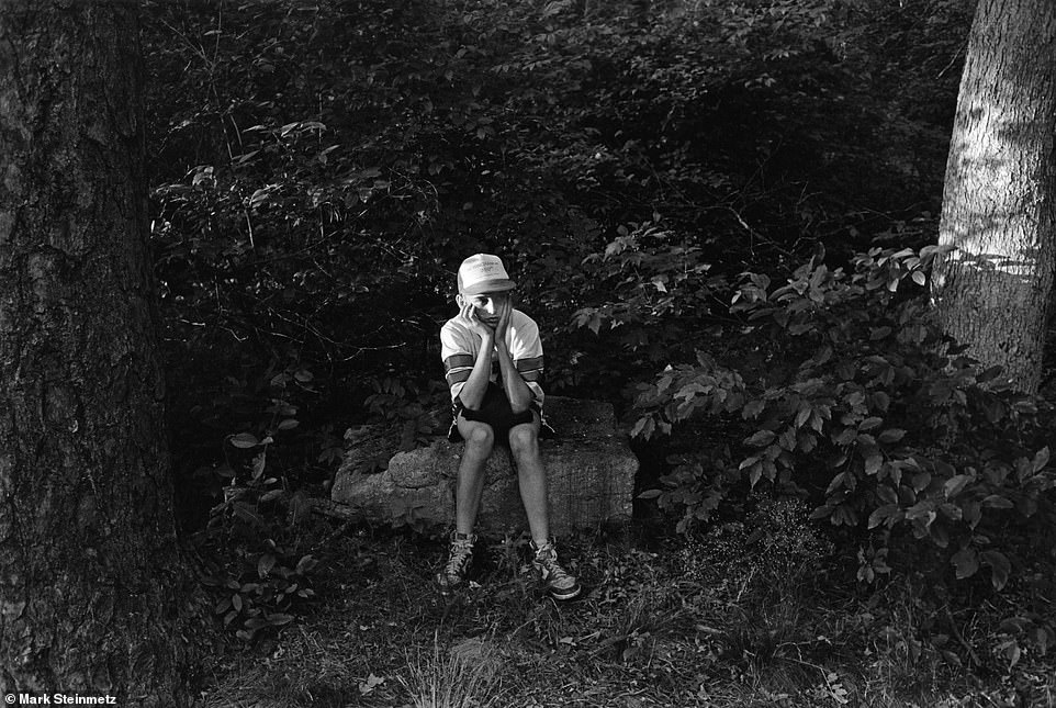 A young boy caught in a moment of tranquility, surrounded by trees and small plants