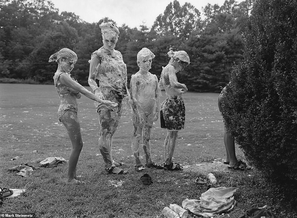 Four kids covered in foam line up for fresh water