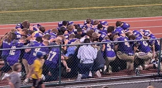 Karns City players and staff take a knee after the 17-year-old was rushed to hospital