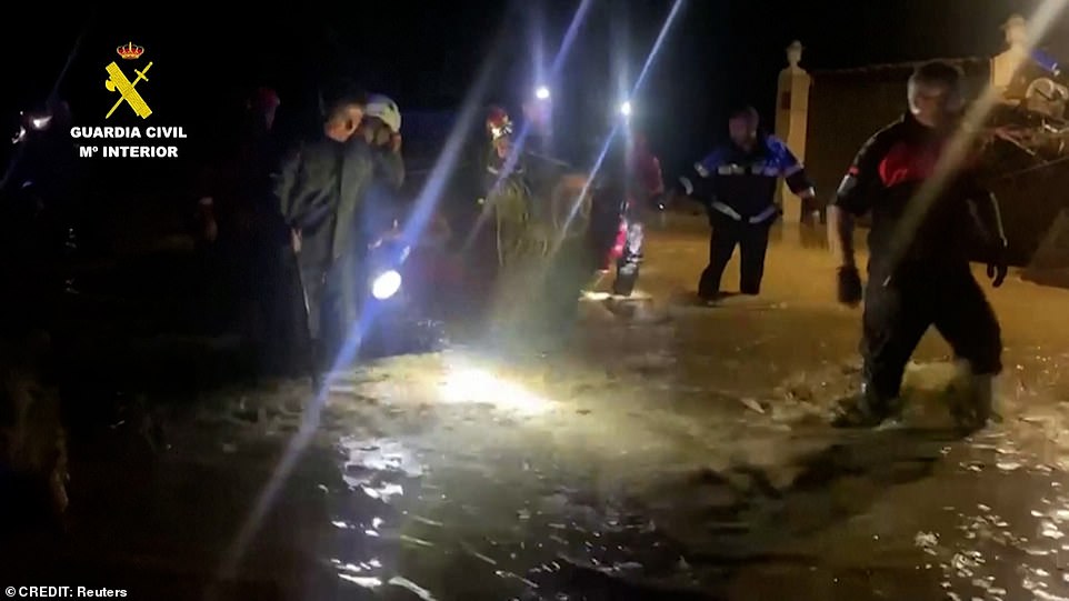 Rescue workers wade through the rushing water to help stranded residents