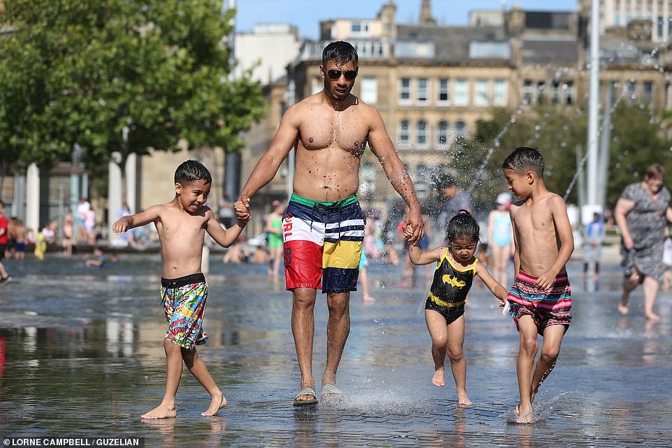 A family enjoys the warm weather in Bradford, West Yorkshire, on Sunday as Britain's temperature is expected to climb into the mid-30s this week