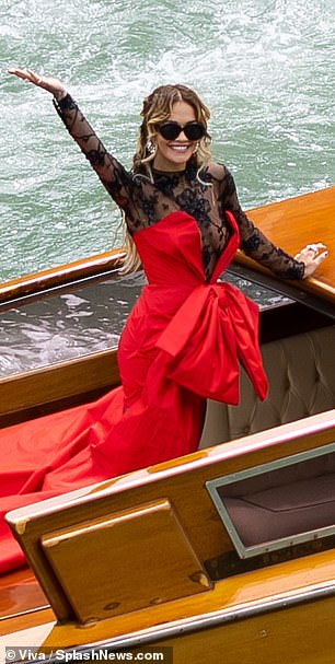 Wow!  To kick off the day of glamour, the RIP singer, 32, threw her arms in the air as her stylist snapped photos of her arriving via boat, dressed in a dramatic outfit consisting of a red satin Moschino dress with a lace bottom layer.