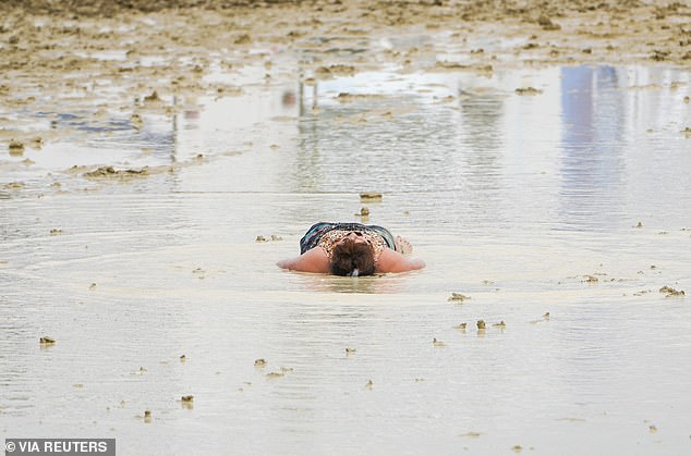 A Burning Man visitor lies in the mud and water during the event