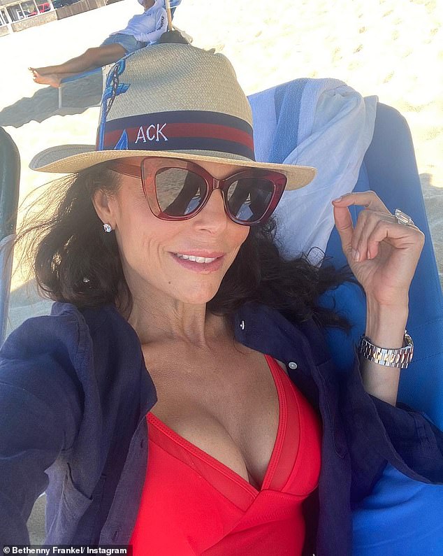 Relaxing: She was spotted wearing a low-cut red dress under a navy blue button-up shirt on a trip to the beach