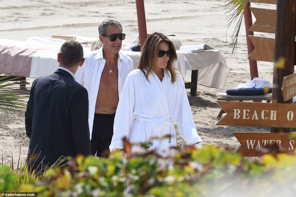 Then Carla donned a white robe, while Sarkozy donned a white shirt as they walked back to their glitzy accommodation.