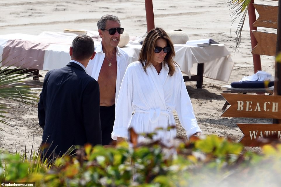 Then Carla donned a white robe, while Sarkozy donned a white shirt as they walked back to their glitzy accommodation.