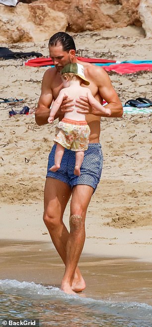 Cuddles: Lewis was seen picking up his son Lucky as the little one paddled in the ocean