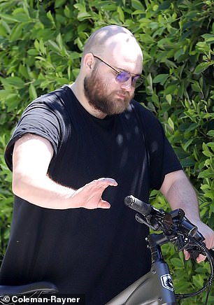 Angus T. Jones pushes his electric bike in LA