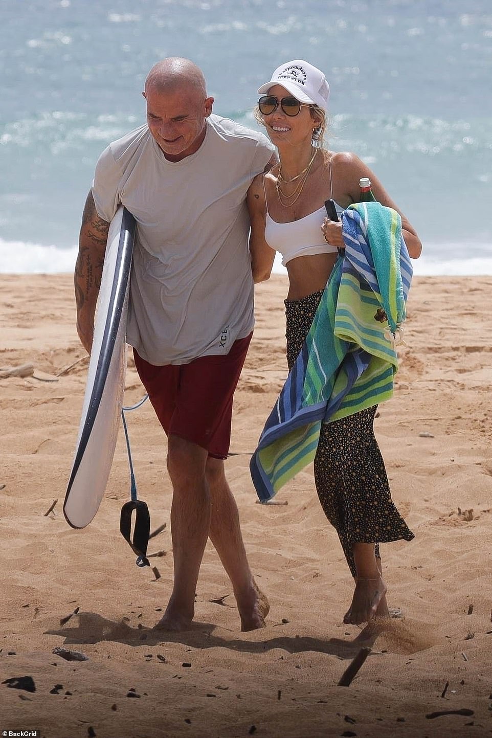 Dommy: He wore a light gray top with maroon shorts as he carried his surfboard onto the beach