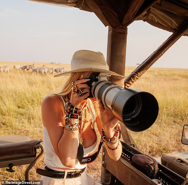 Photographer: The mother of one of them was her usual fashion shot as she snapped photos of the wildlife, including a lounging female lion, a herd of buffalo, a stately giraffe, several zebras and a majestic male lion with a beautiful mane