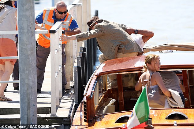 Helping hand: He then climbed into the boat, aided by two men, where he was joined by the couple's adopted daughters, Manzie Tio, 23, and Bechet, 24.