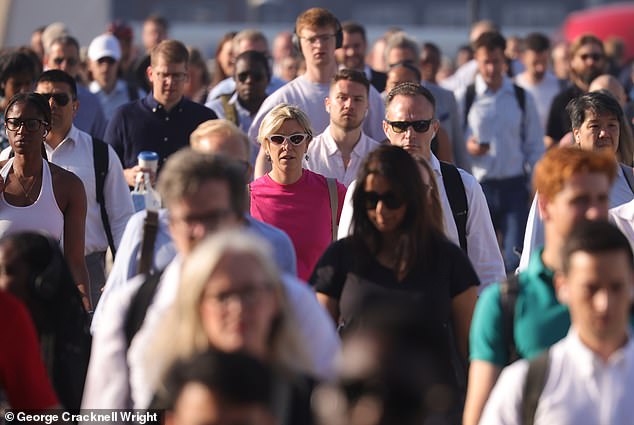 Commuters cross London Bridge this morning during warm and sunny weather in the capital