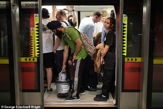 Commuters board the London Underground today during the heat wave.  The temperature in the capital is expected to reach 32 degrees Celsius today