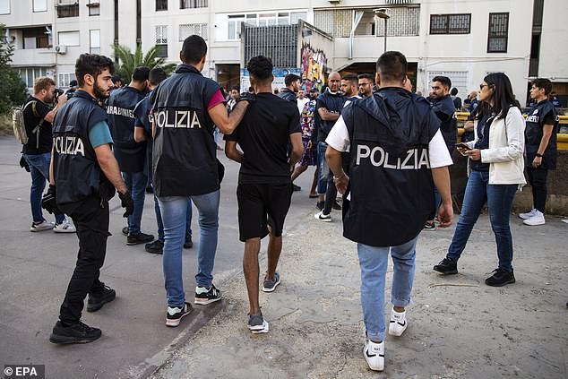 A man is detained as special police forces raid the mafia in Rome, Italy, on Thursday