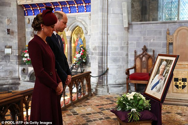 Kate pauses at the flowers she laid at St. David's Cathedral in Wales this afternoon