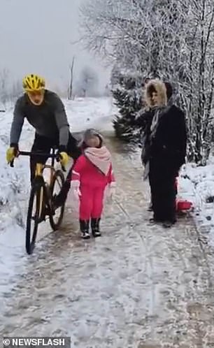 The cyclist slams his knee into the girl, causing her to fall to the ground