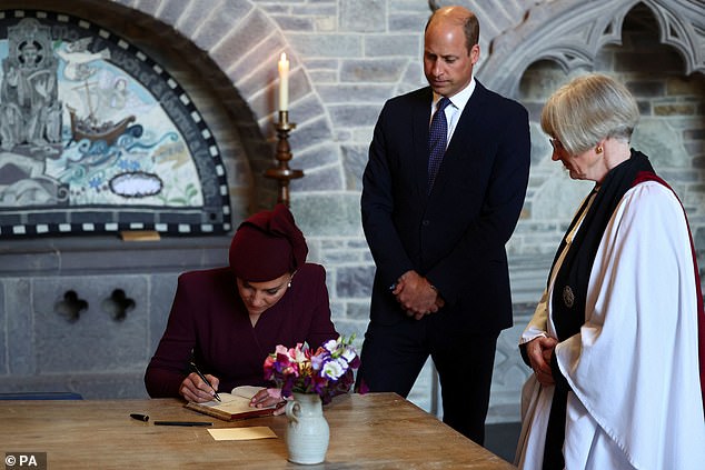 The Princess of Wales, accompanied by the Prince of Wales and Sarah Rowland Jones, Dean of St David's Cathedral, signs the visitors' book at St David's Cathedral in Wales today