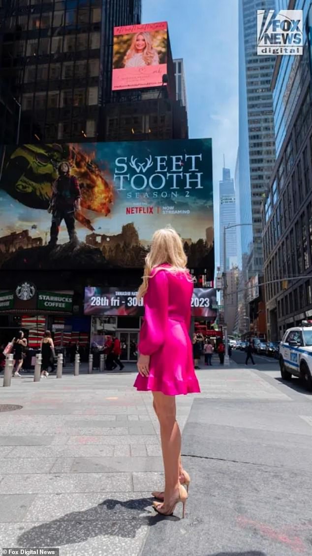 Maddie Brooks' mother, Ashley Baustert, stands in front of the Times Square billboard memorializing her daughter and promoting the nonprofit created to help those in financial need in honor of Brooks