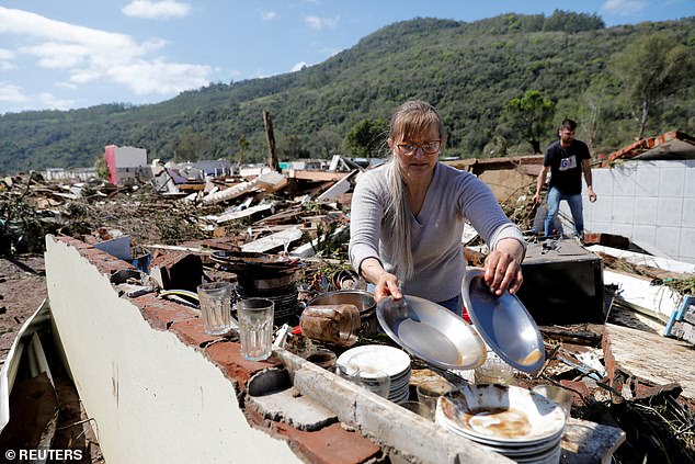 Muçum residents Silvana Primel and Jose Gabriel pick up objects in the ruins of their home