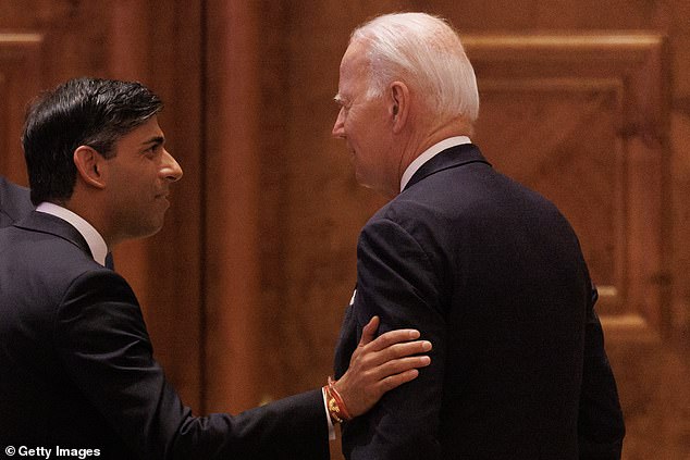 British Prime Minister Rishi Sunak (left) pats President Joe Biden (right) on the shoulder as he arrives at the G20 leaders' summit in New Delhi, India on Saturday