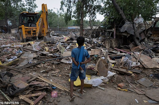 Ishant Kumar, 10, son of Dharmender Kumar, who works as a clerk at Pragati Maidan, where the main venue of the G20 summit is located, stands next to his bulldozed house during a demolition drive by authorities in a slum near the upcoming summit venue in New Delhi, India, June 1, 2023