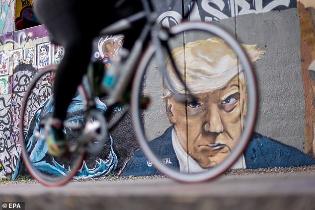 A person cycles past artist Chris Veal's depiction of former U.S. President Donald Trump's booking photo, painted Wednesday along the Atlanta BeltLine Eastside Trail