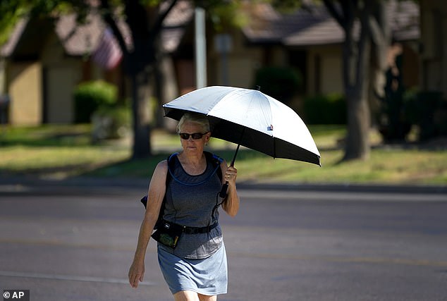 A woman uses an umbrella for shade to combat the high temperatures in Phoenix on Monday